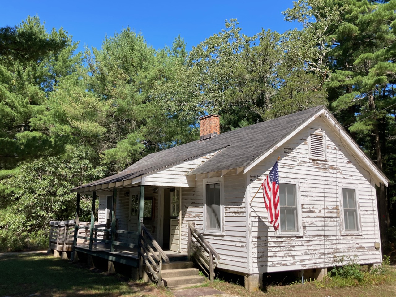 White sided one-story house with American flag hanging from side.