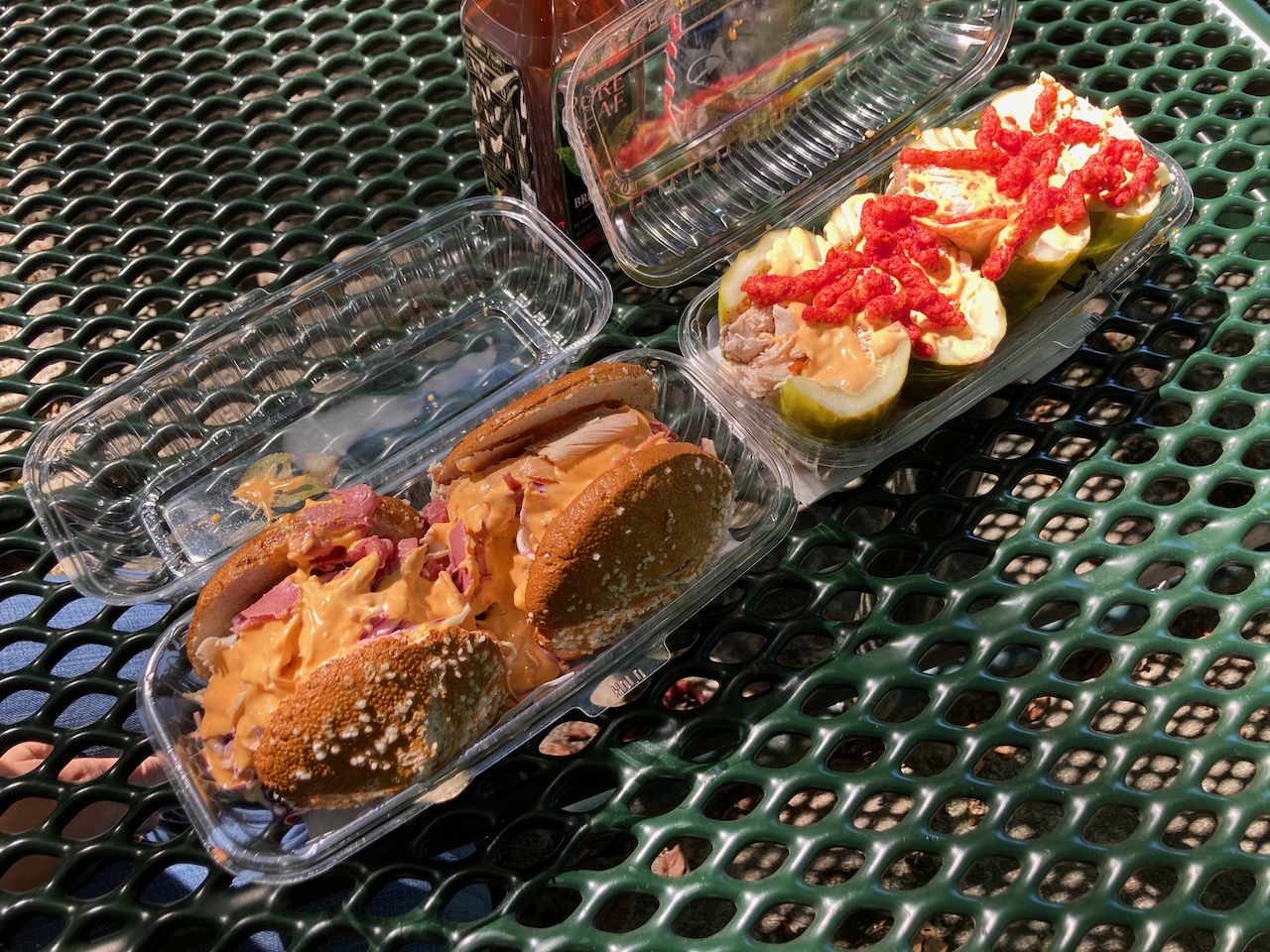 Sandwiches in plastic containers on picnic table.