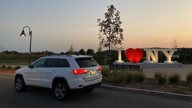 2014 white Jeep Grand Cherokee parked in front of I LOVE NEW YORK sign.