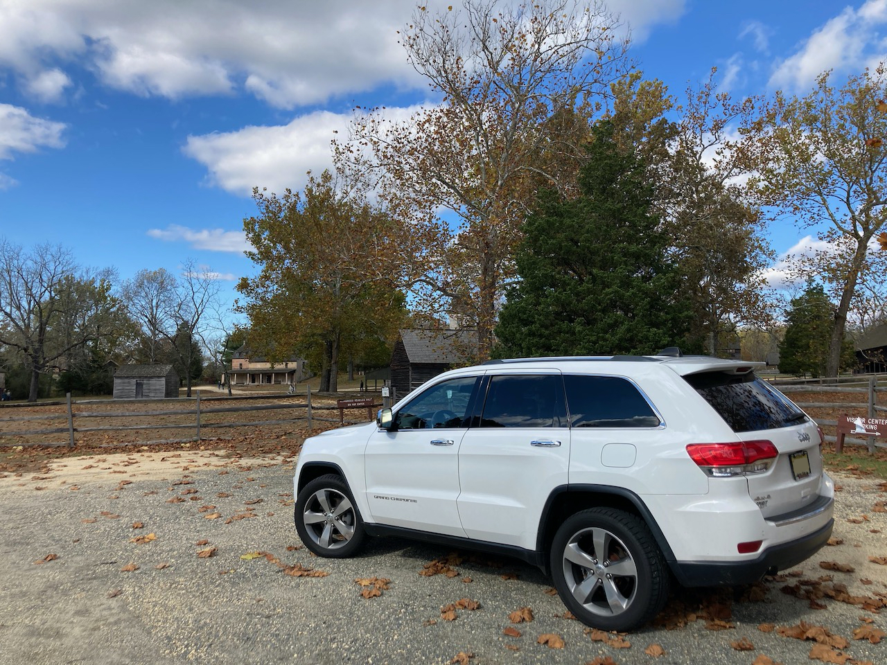 White 2014 Jeep Grand Cherokee parked in front of historic village.
