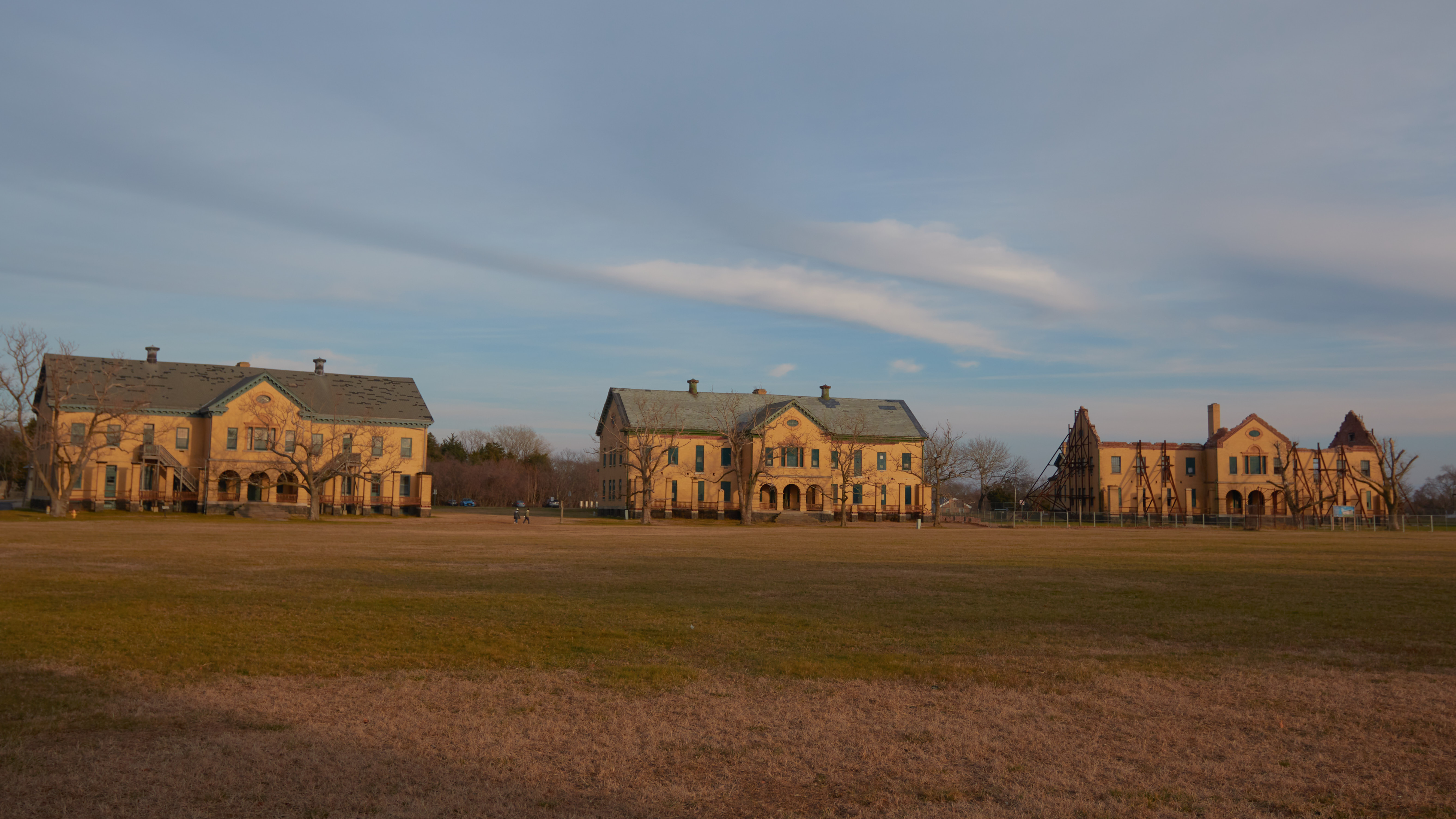 Row of large administrative buildings across open grassy field.