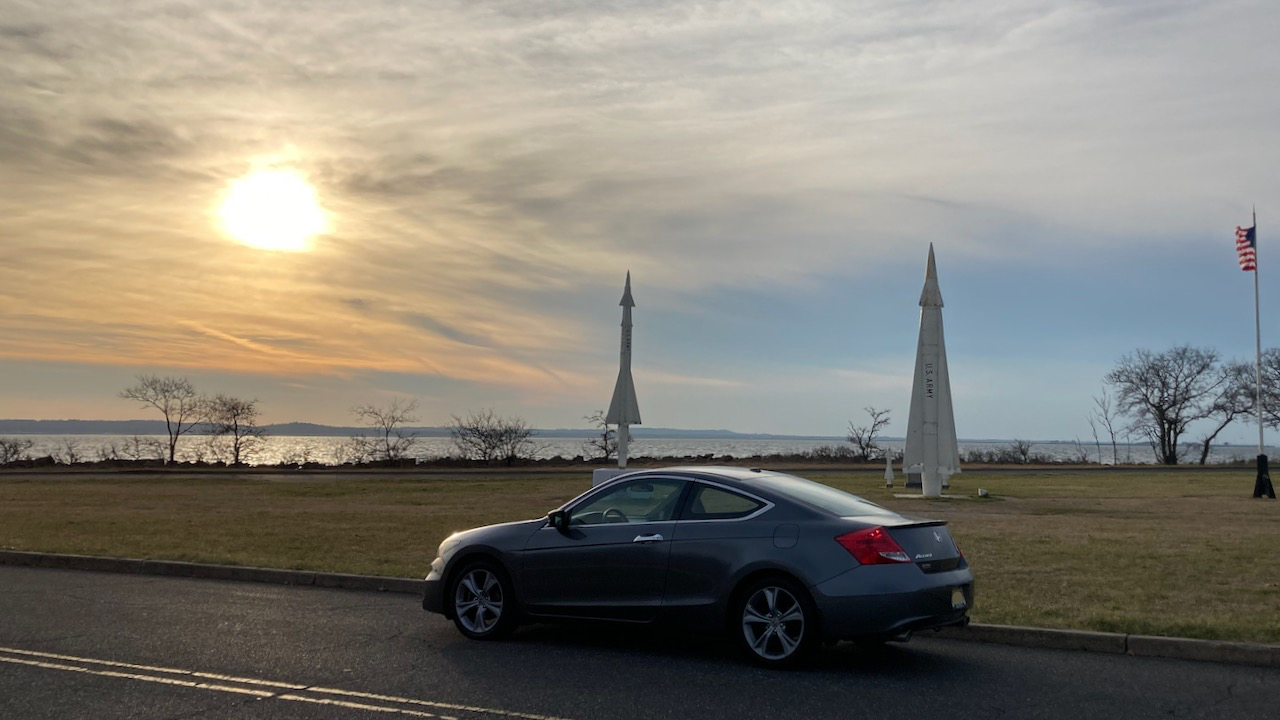 2012 Honda Accord parked in front of missiles on pedestals.