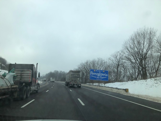 View of highway with sign that says WELCOME TO PENNSYLVANIA along right shoulder.