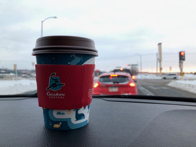 Cup of Caribou coffee on dashboard.