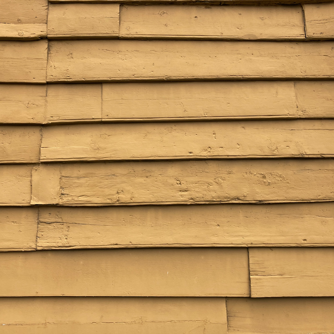 Clapboard siding, painted yellow.