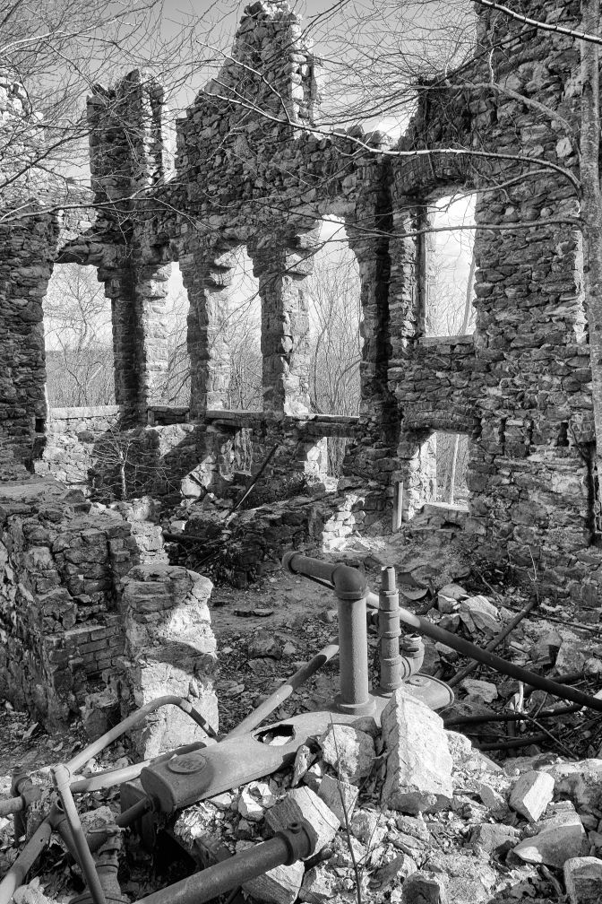 Ruins of interior of building, including pipework.