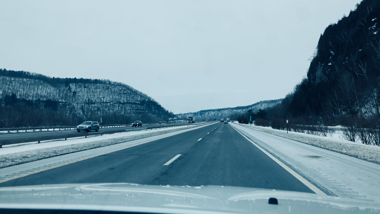 View of New York Thruway, with hillsides covered in snow.