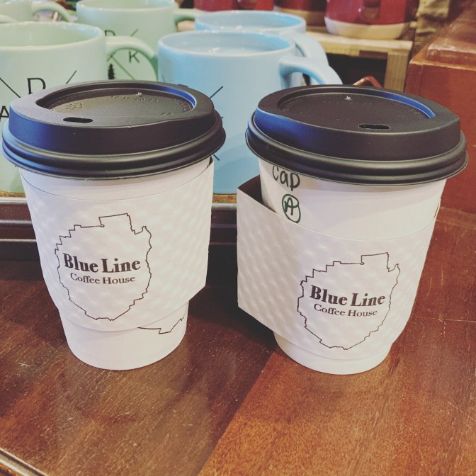Two paper cups that say BLUE LINE COFFEE HOUSE