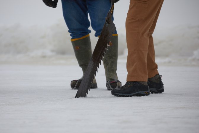 Volunteers cutting ice from lake.