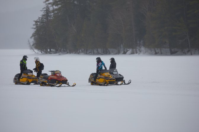 Snowmobilers parked on ice.