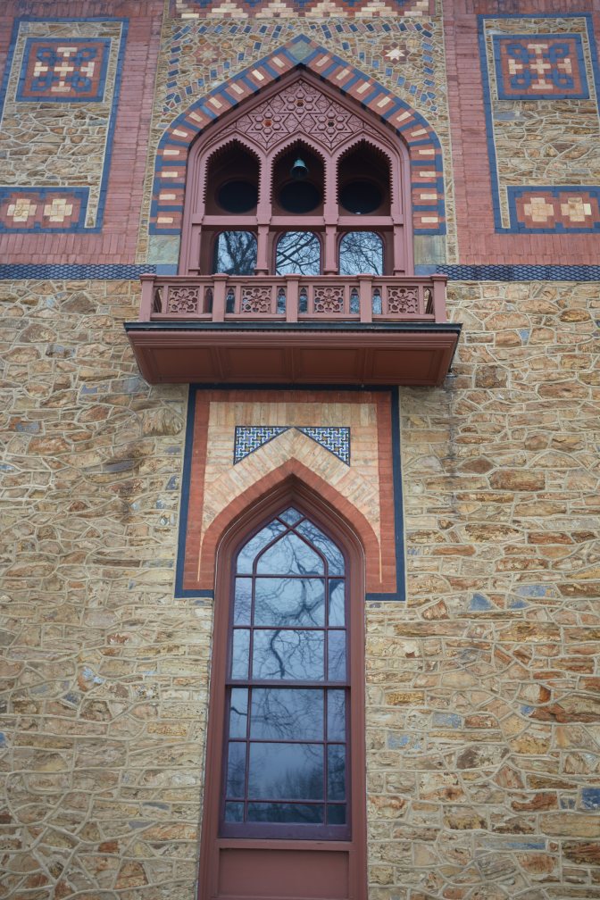 Section of house include first-floor window and second-floor window with elaborate exterior designs.