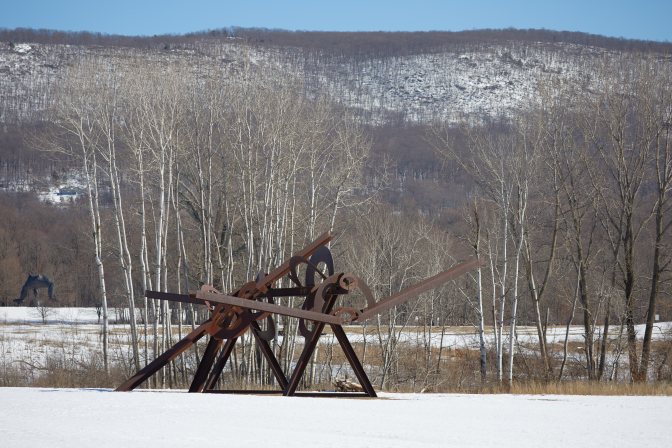 Sculpture on snow, with mountains in background.
