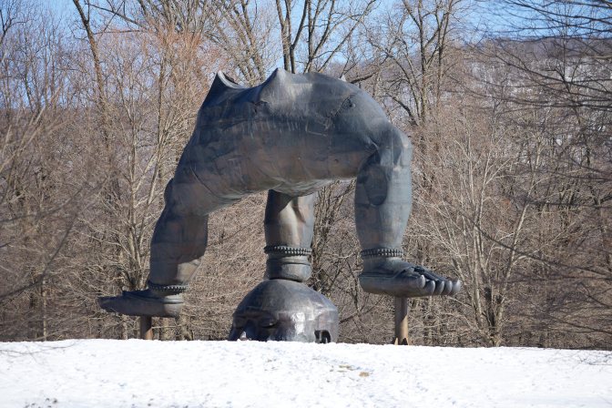 Statue of Buddha holding himself up with his head on ground.