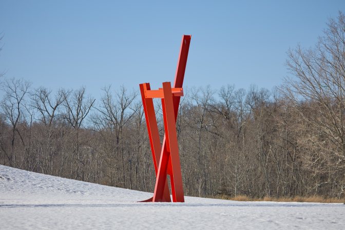 Sculpture of red girders intertwined.