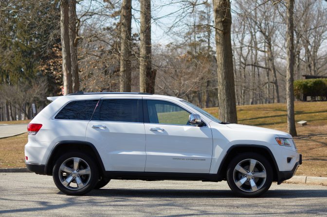 White Jeep Grand Cherokee parked in lot in public park.