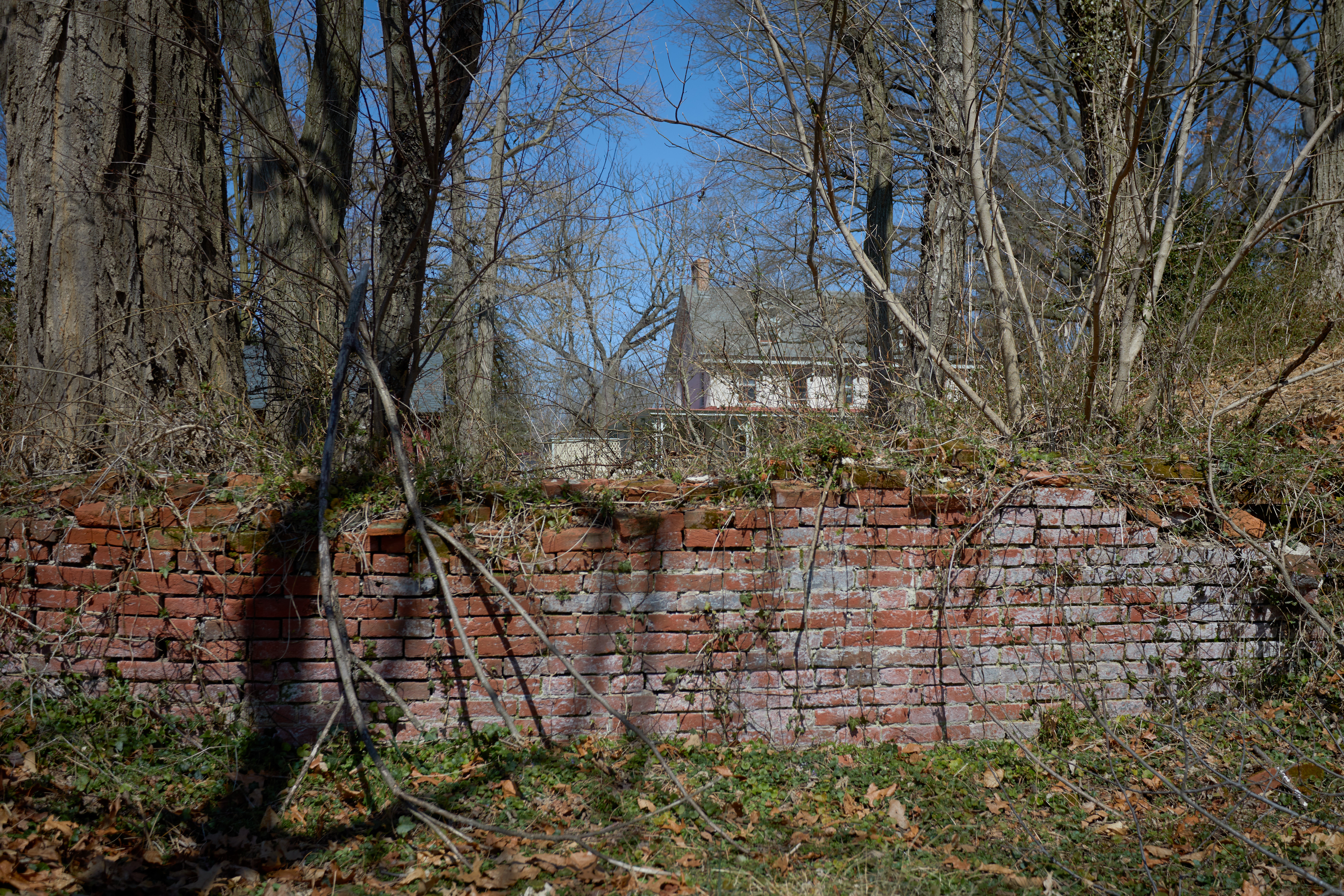 Remnants of brick wall with mansion in distance.