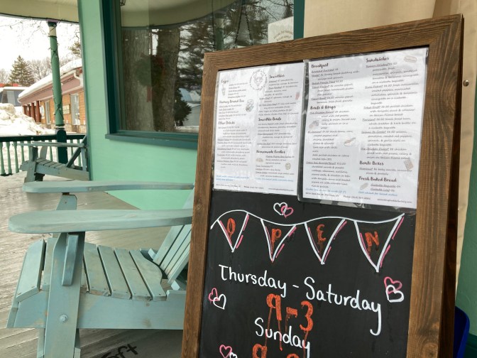 Sandwich board outside of cafe that has menu and hours of operation.