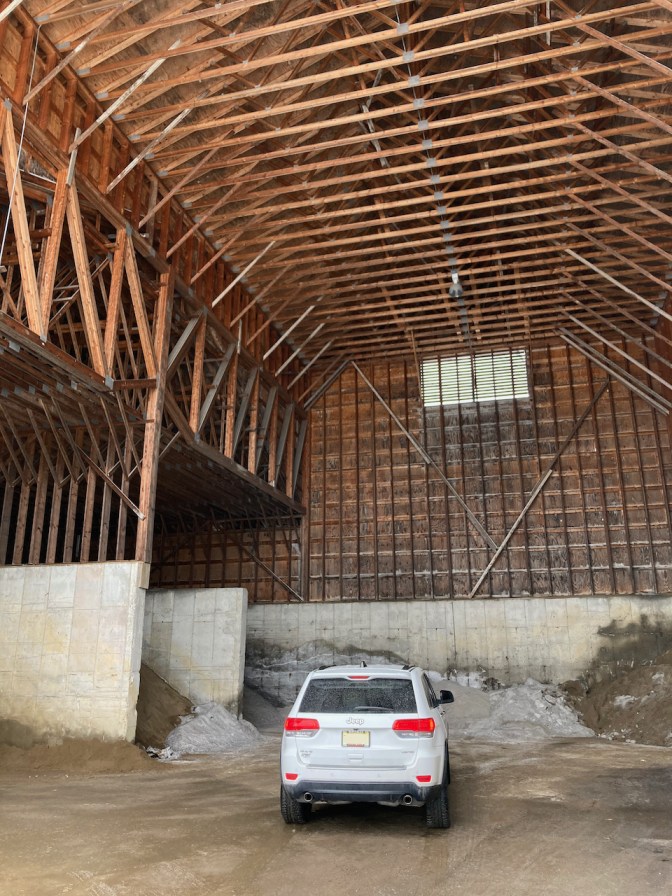 White Jeep Grand Cherokee parked in enormous building holding salt and sand.