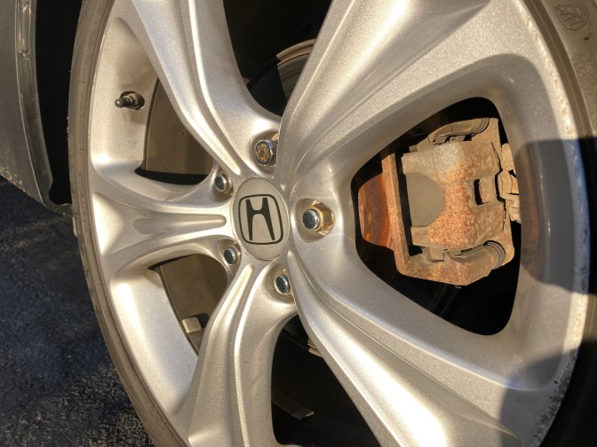 View of car wheel, with focus on brake caliper.