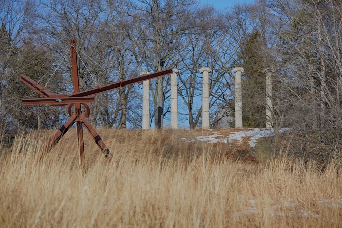Mon Père Mon Pire sculpture in foreground, with Greek columns up hill in background.