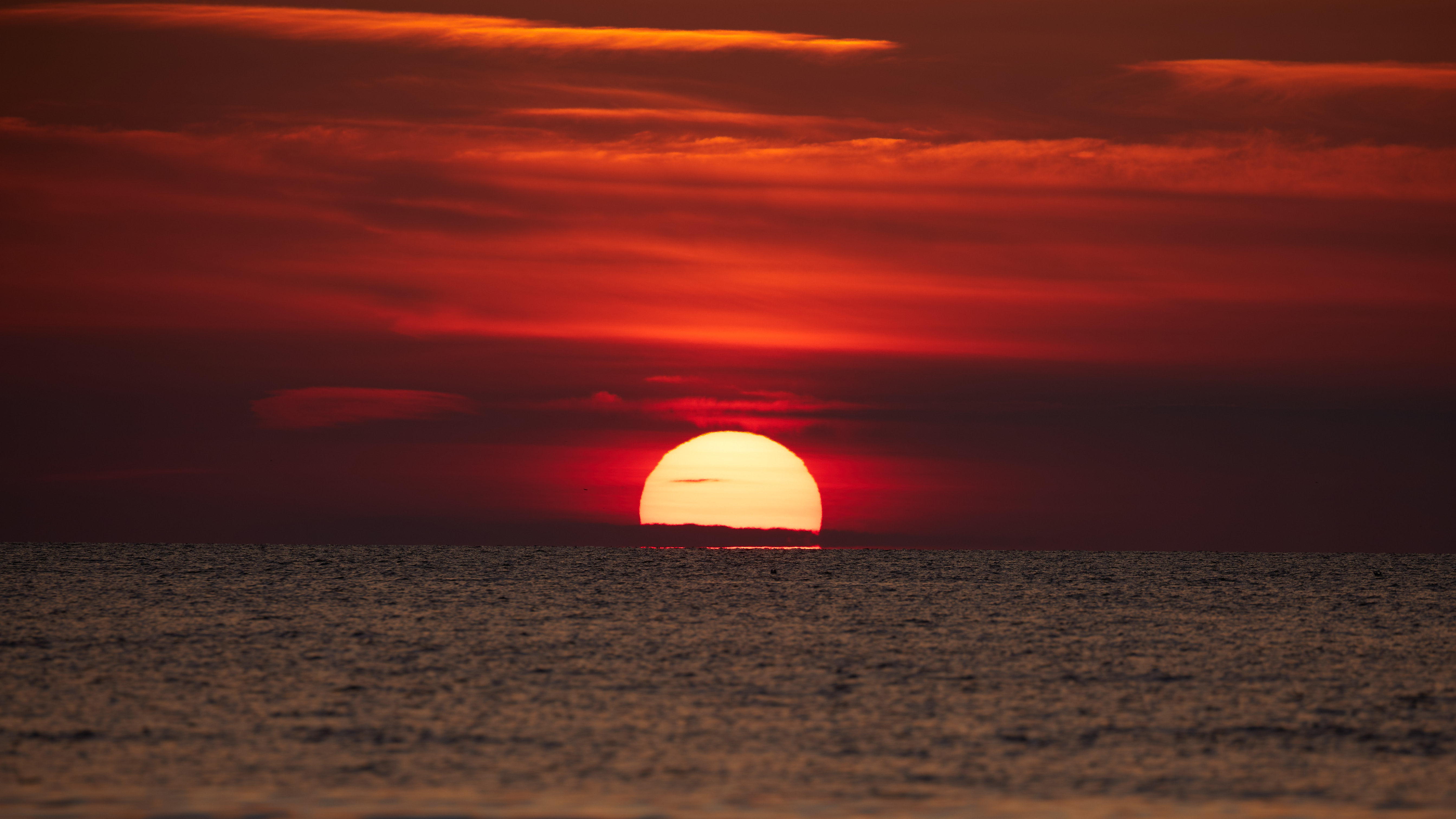 Sunset with red sky, over ocean.