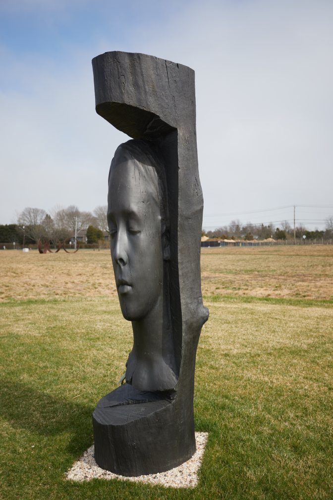Sculpture of woman's head in cut away from stone.