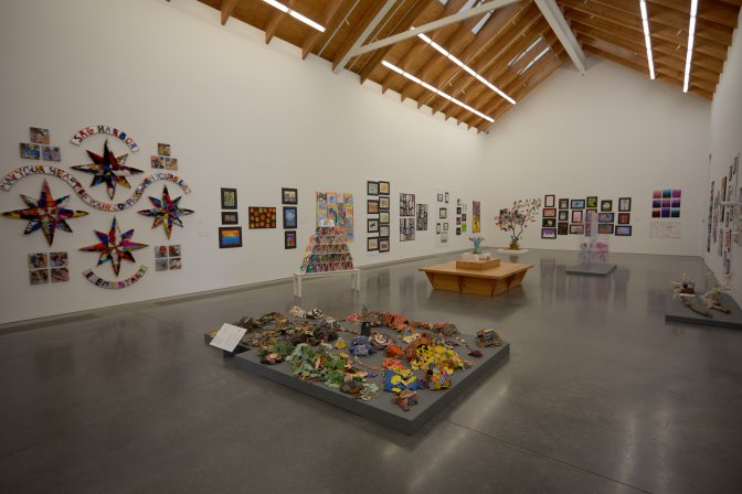 Interior of gallery, with art on walls and on floor displays.