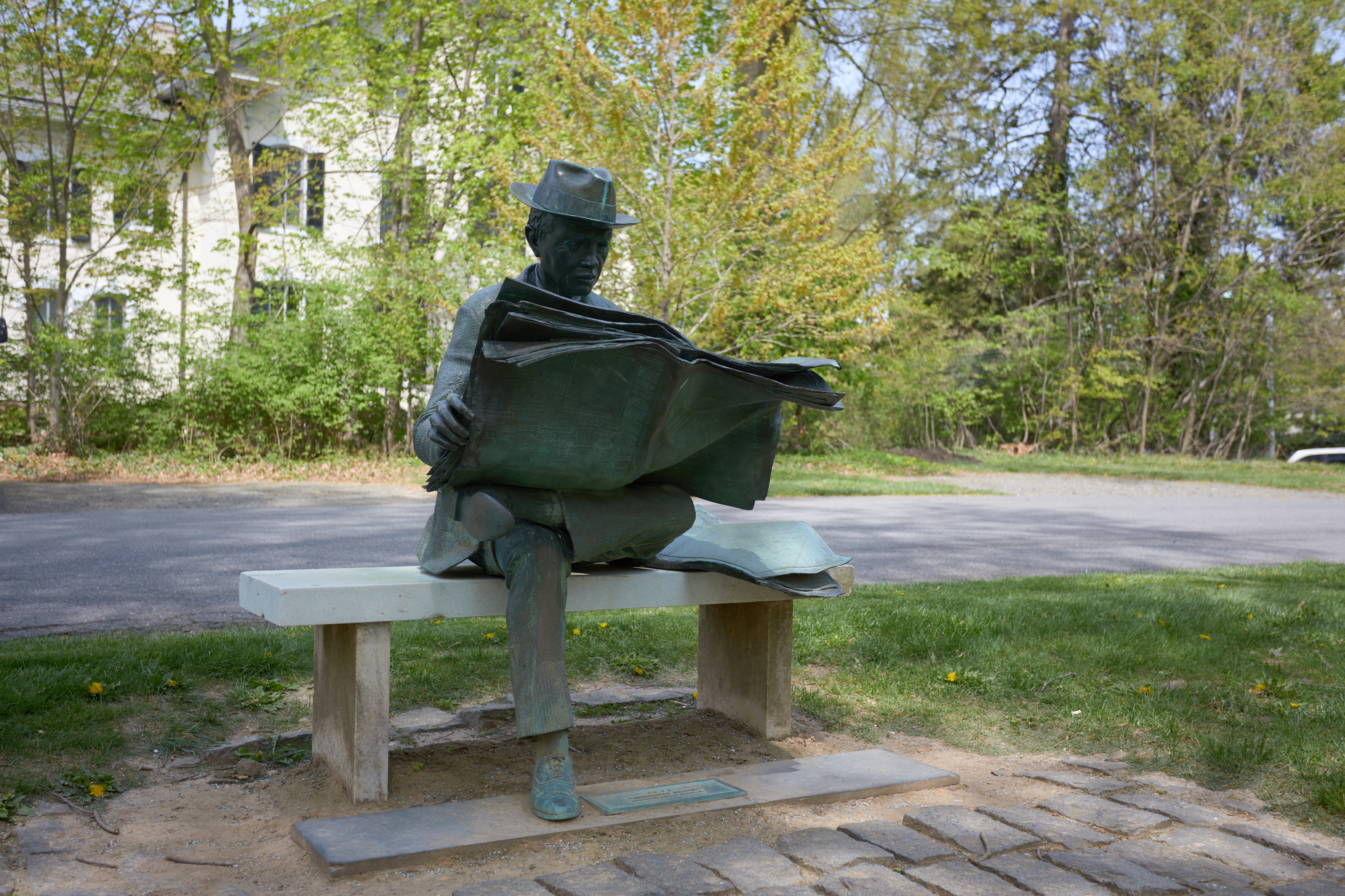 Statue of man reading newspaper.