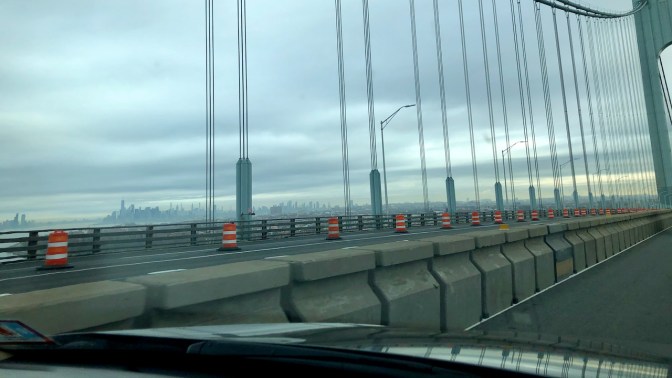 View of Manhattan skyline in distance from top of bridge.