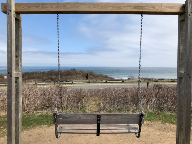 Swing bench with view of ocean in distance.