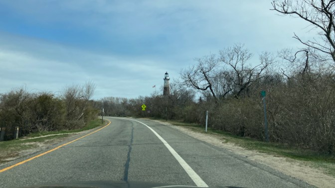 Top of Montauk Point Light in distance along road.