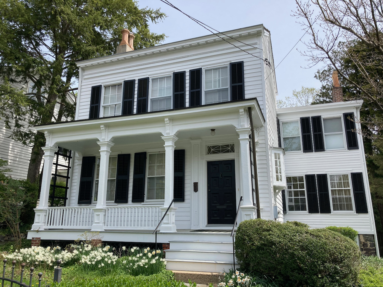 Exterior of white house with black shutters around windows.