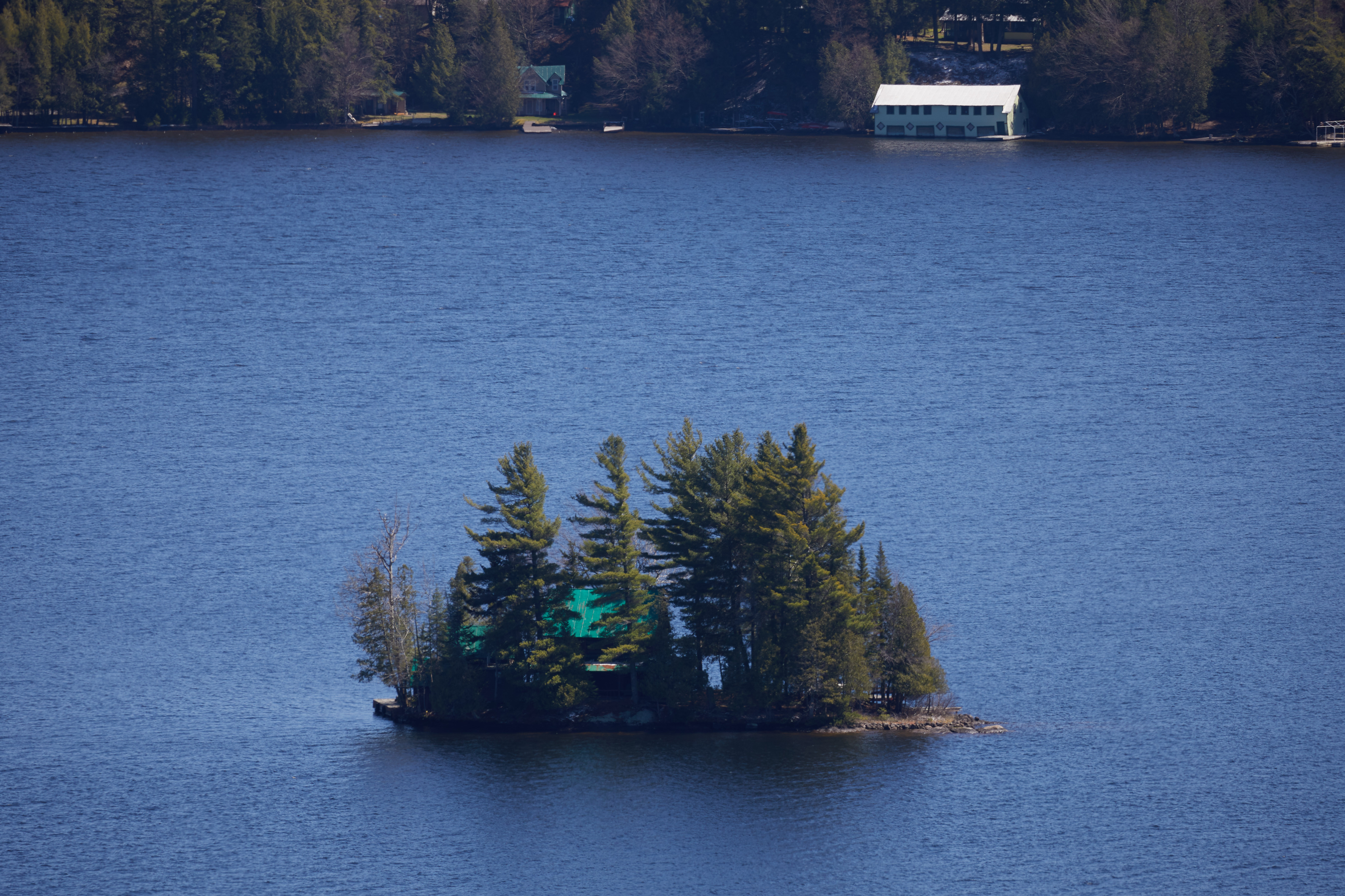 View of small island in lake with house on it.
