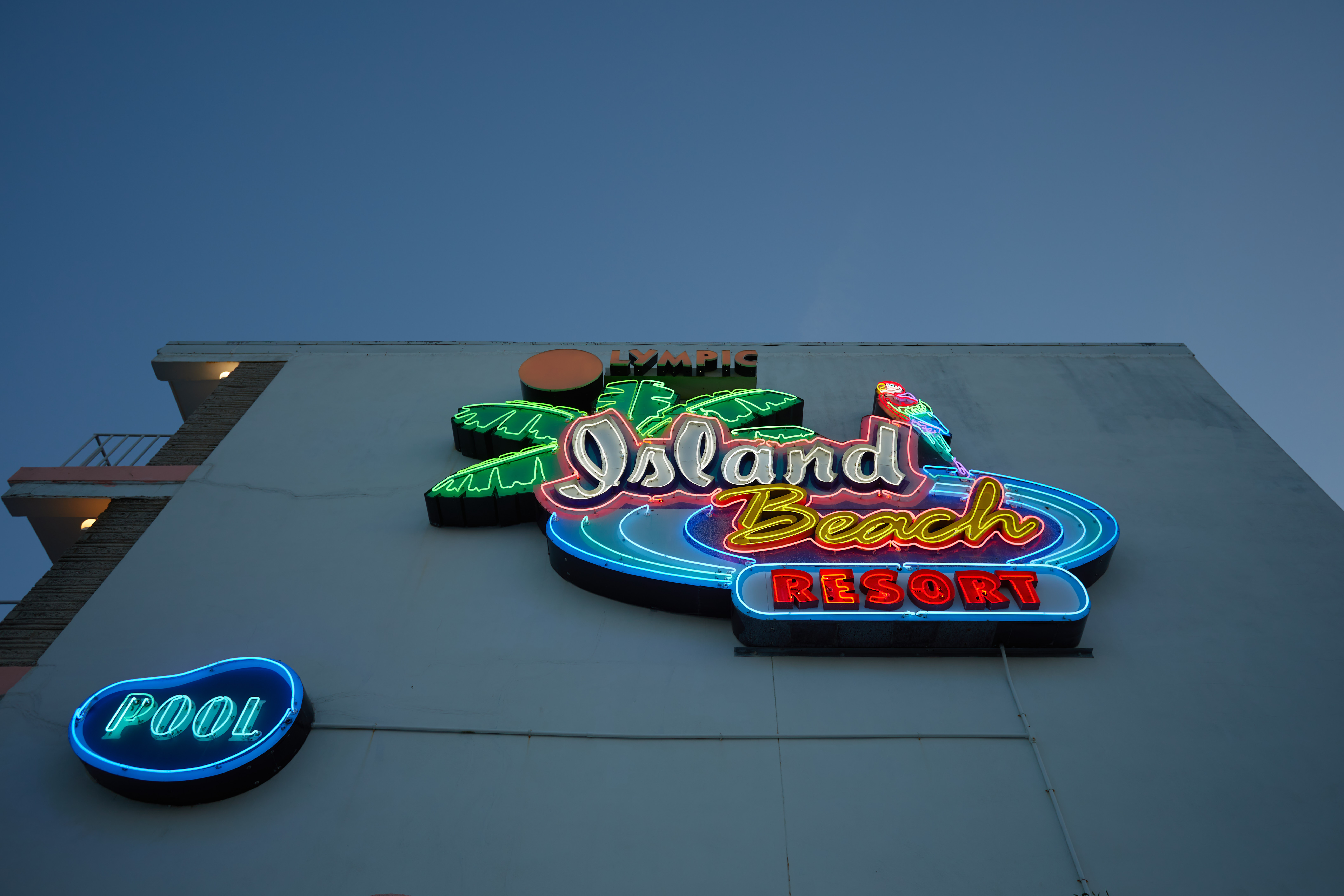 Neon sign on side of building that reads Olympic Island Beach Resort