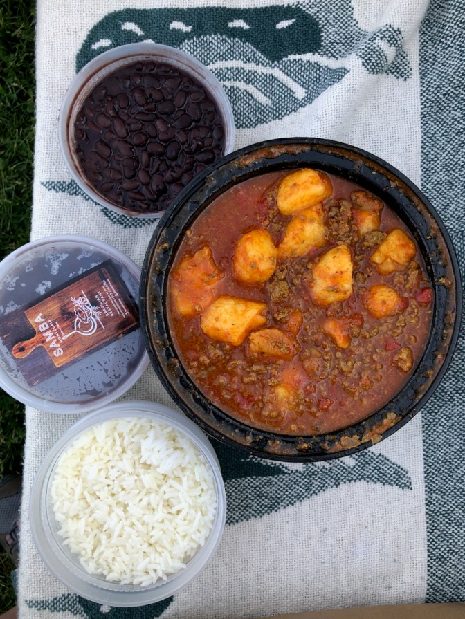 Plastic containers of food - one with white rice, one with black beans, and one with meat gnocchi.