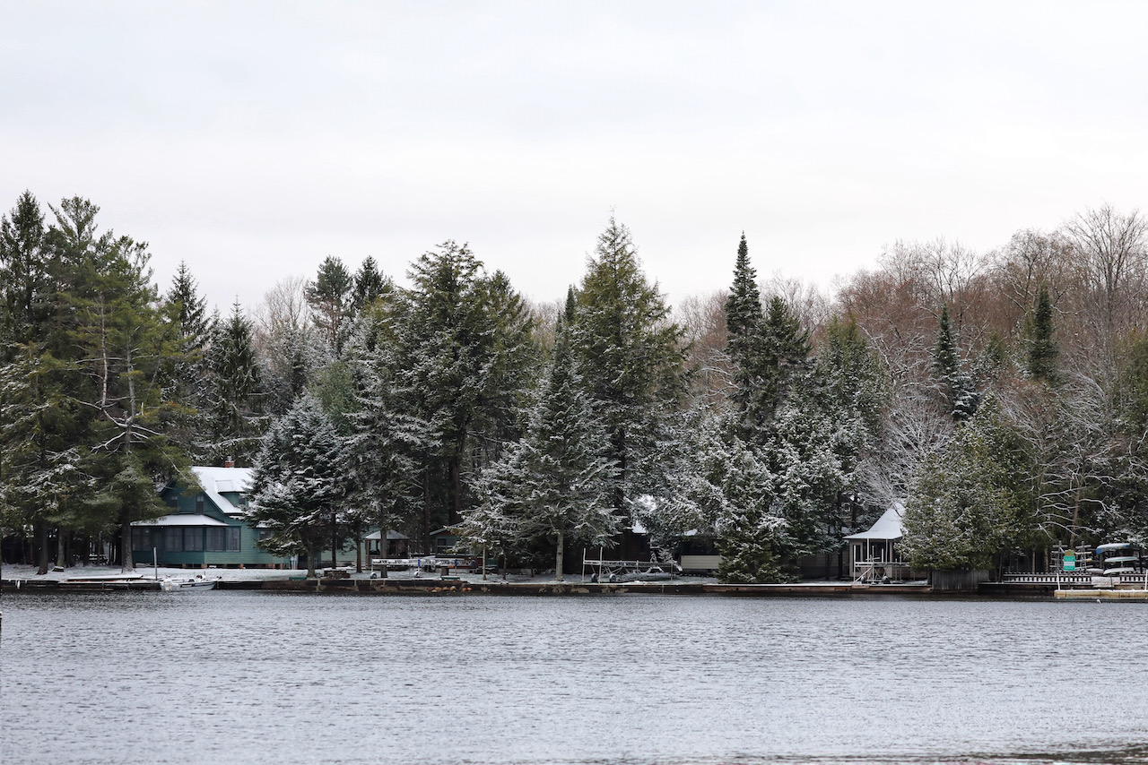 Snow-covered trees and homes along shoreline.