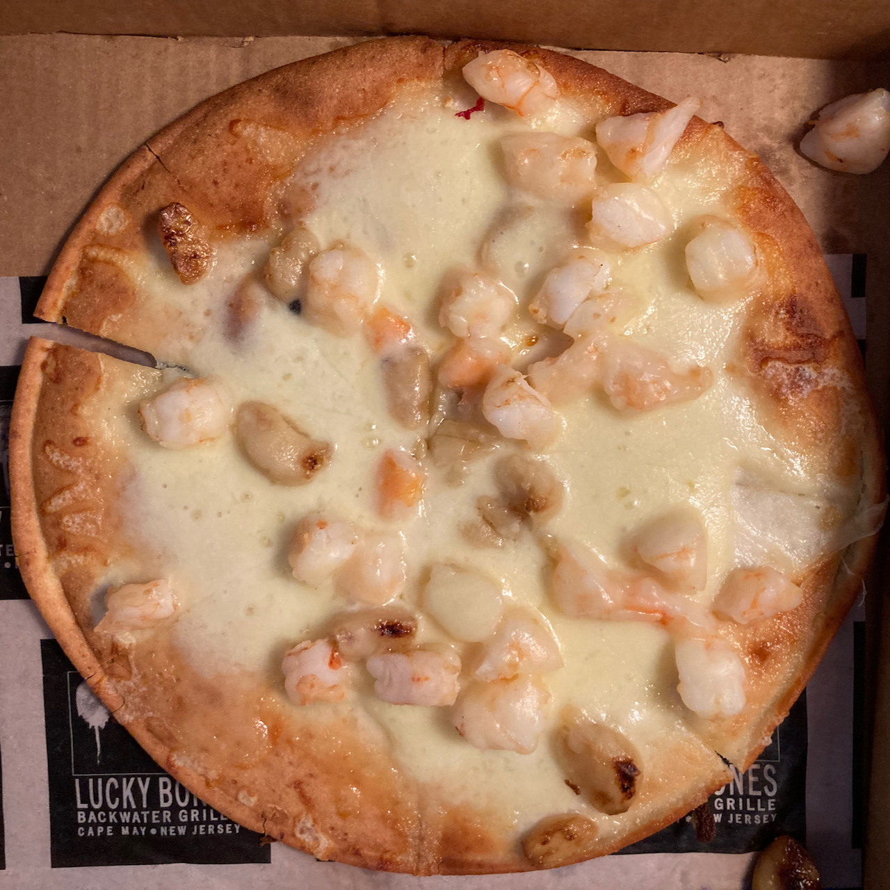 Pizza covered in cheese, garlic, and shrimp.