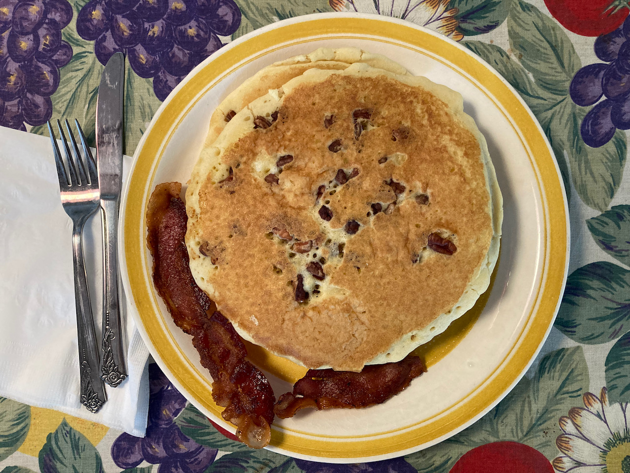 Pecan pancakes and bacon on plate.