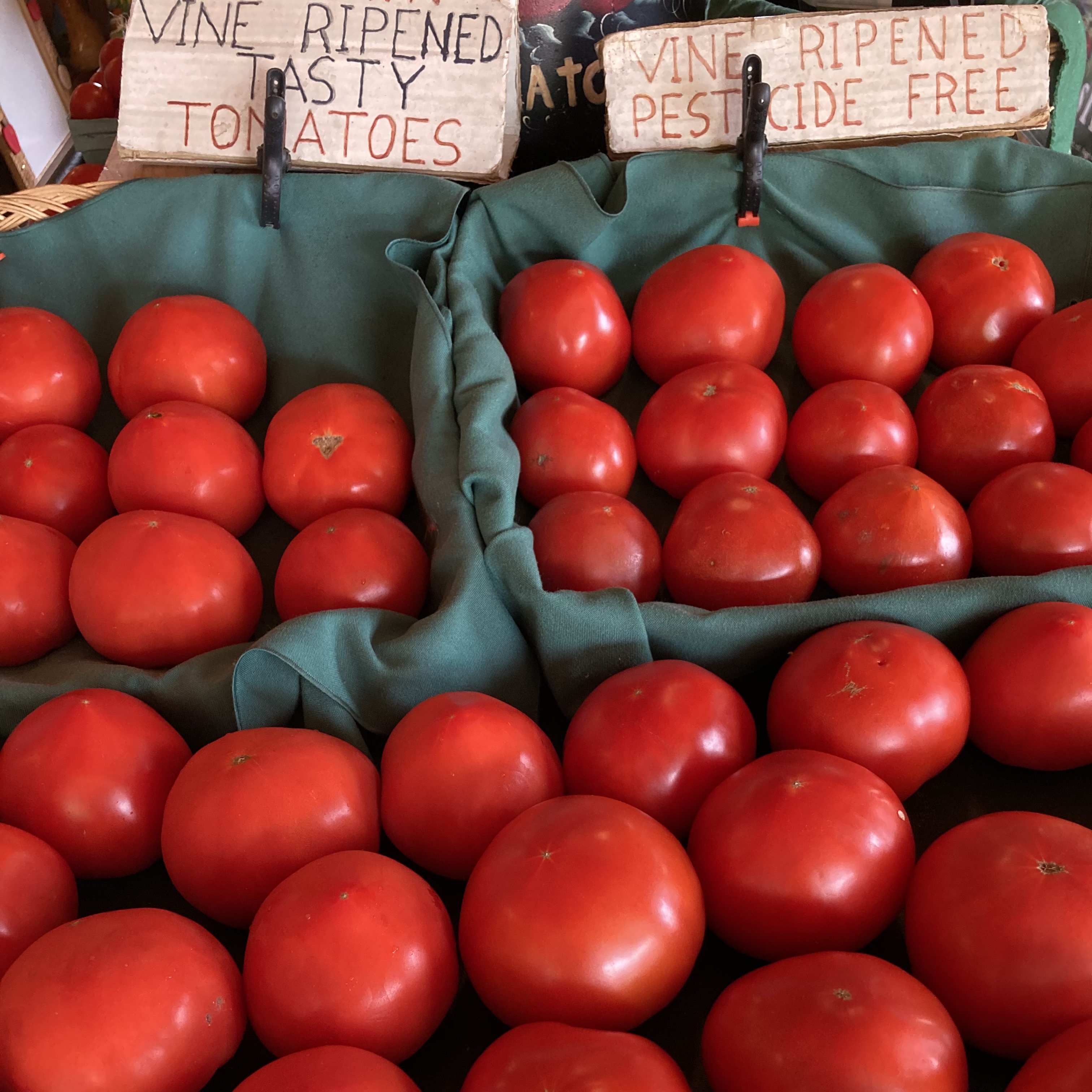 Stand of red tomatoes, with sign that says VINE RIPENED TASTY TOMATOES