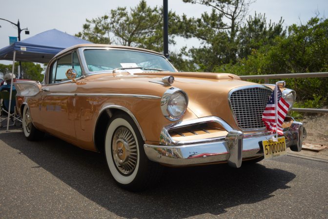 Gold Studebaker coupe parked on promenade.