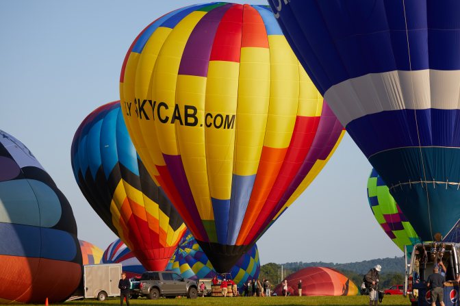 Three balloons, inflated, on ground, and preparing to fly.