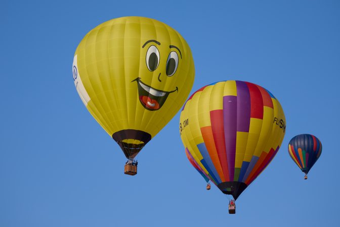 Two multicolored balloons, and yellow ballon with smiley face.