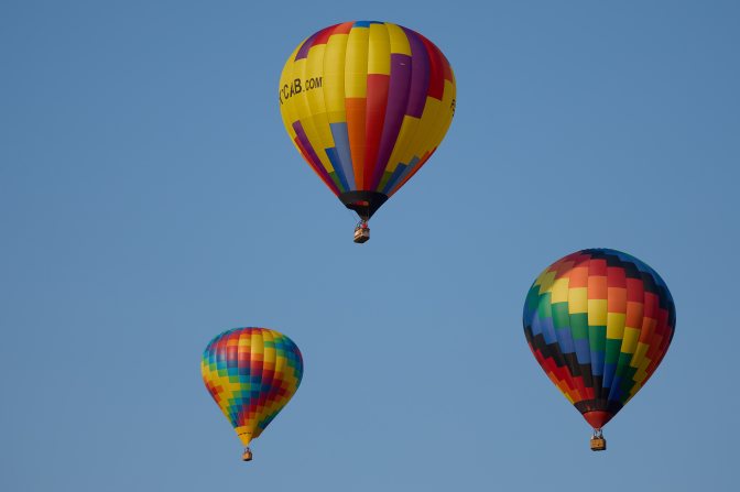 Three multicolored balloons in air.