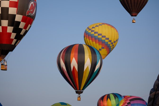 Several multicolored balloons rising into the sky.