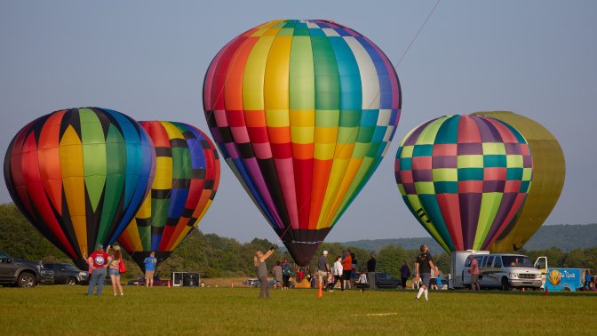 Four multicolored balloons on ground, awaiting takeoff.