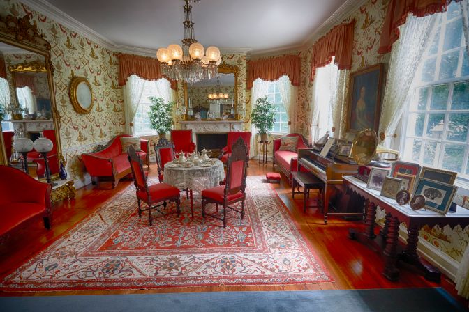Formal parlor, with table set for tea, piano, and sofas.