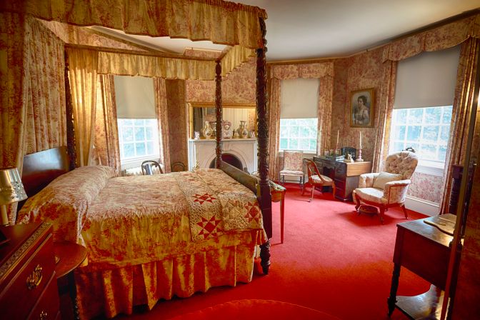 Bedroom with red carpet, and decorative red wallpaper.