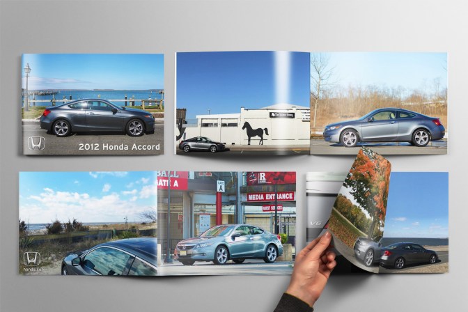 Brochures with photos of 2012 Honda Accord on table, with hand of person flipping through one of the brochures.