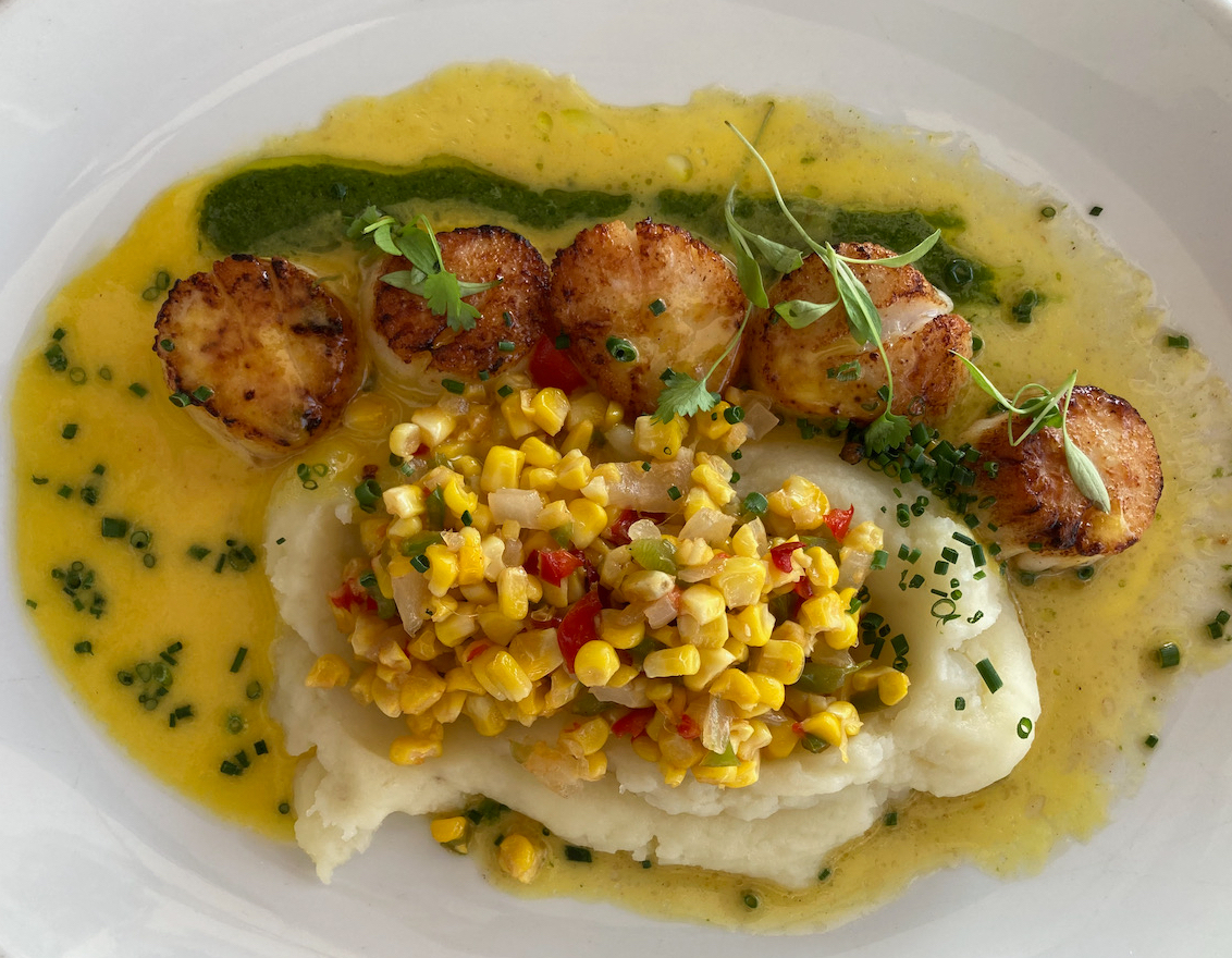 Broiled scallops, corn, and mashed potatoes on a plate.