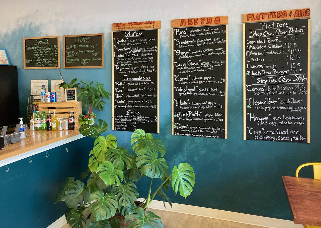 Interior of Que Ricas restaurant, with blackboard menus on wall.